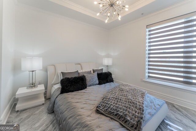 bedroom with wood finished floors, baseboards, an inviting chandelier, a tray ceiling, and ornamental molding