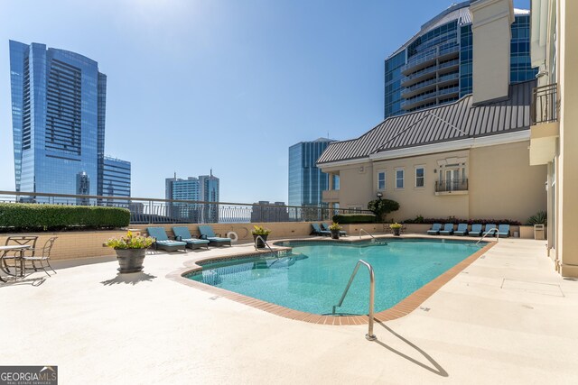 community pool with a city view and a patio