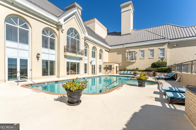 pool with french doors and a patio