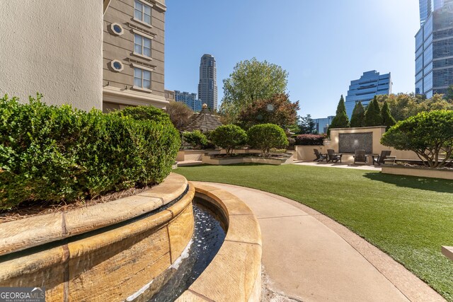 view of home's community featuring a patio area, a lawn, and a view of city