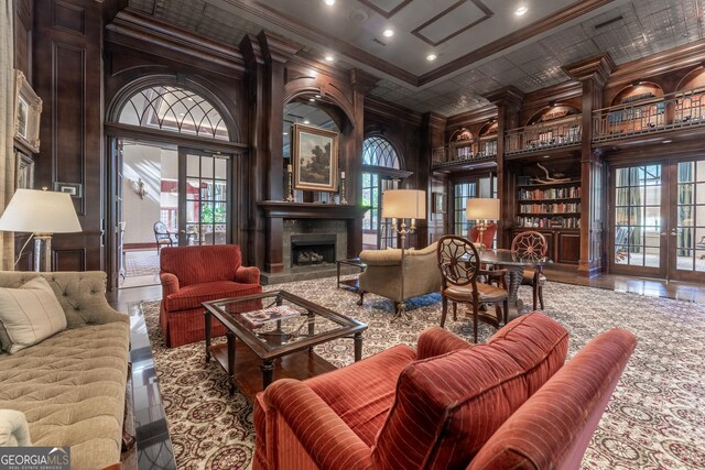 living room with a towering ceiling, french doors, ornamental molding, and a fireplace