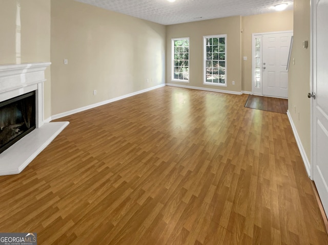 unfurnished living room with light hardwood / wood-style flooring and a textured ceiling