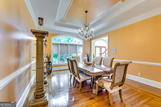 dining area with wood-type flooring, a notable chandelier, and a raised ceiling