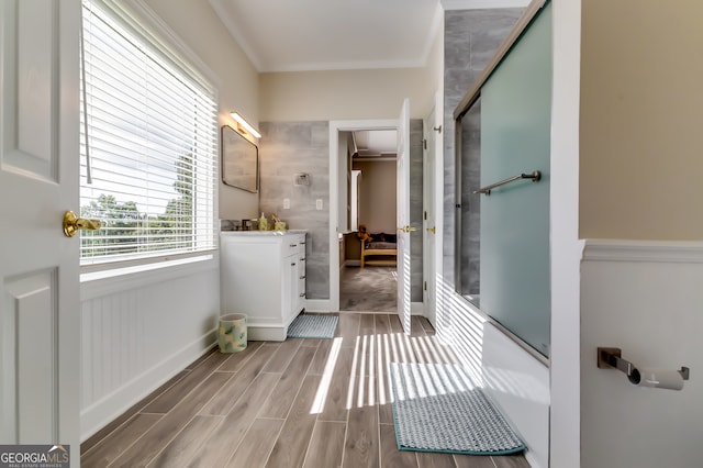 bathroom featuring wood-type flooring, crown molding, a shower with door, and vanity