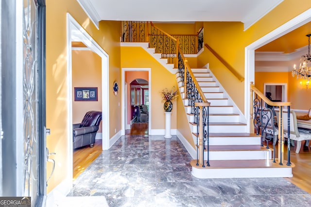 entryway featuring wood-type flooring, crown molding, and an inviting chandelier