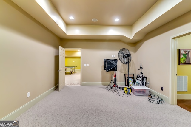 workout room with a tray ceiling and carpet