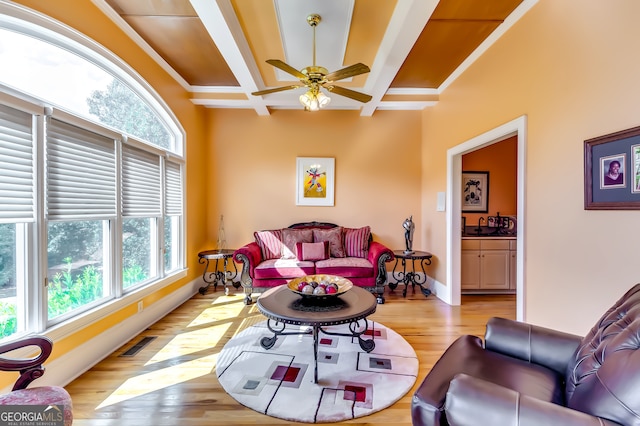 living room with beam ceiling, coffered ceiling, light wood-type flooring, and ceiling fan