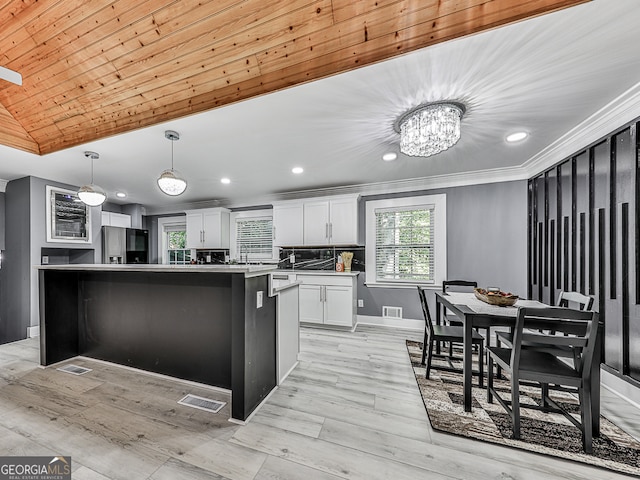 kitchen featuring light hardwood / wood-style floors, stainless steel refrigerator, hanging light fixtures, white cabinets, and a center island