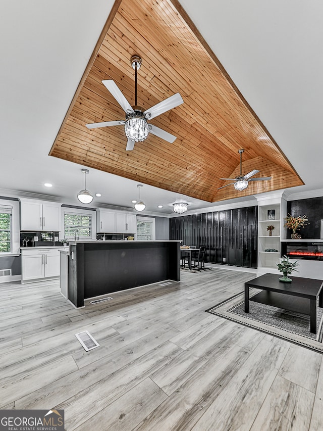 living room with built in features, ceiling fan, lofted ceiling with skylight, wooden ceiling, and light hardwood / wood-style flooring