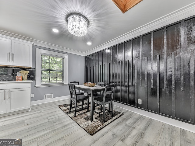 dining room featuring crown molding, an inviting chandelier, and light hardwood / wood-style floors