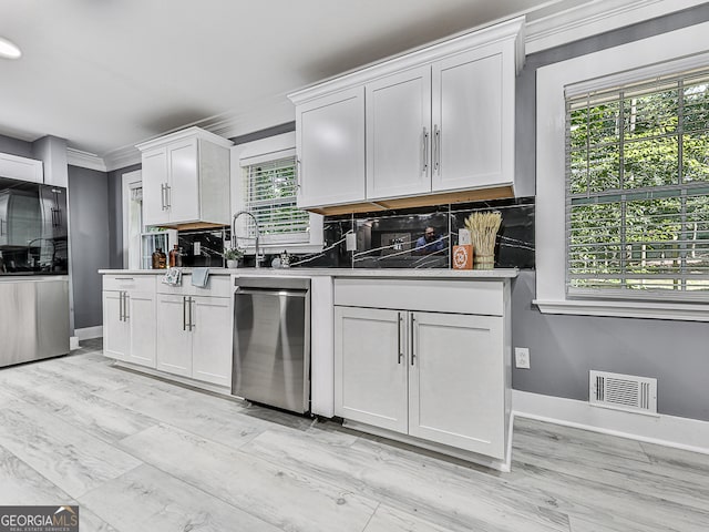 kitchen with backsplash, white cabinets, appliances with stainless steel finishes, and crown molding