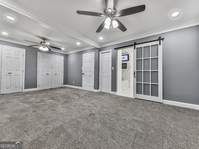 interior space with carpet floors, ceiling fan, and a barn door