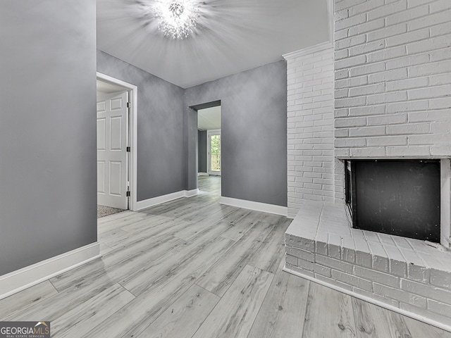 unfurnished living room with a brick fireplace and light hardwood / wood-style flooring