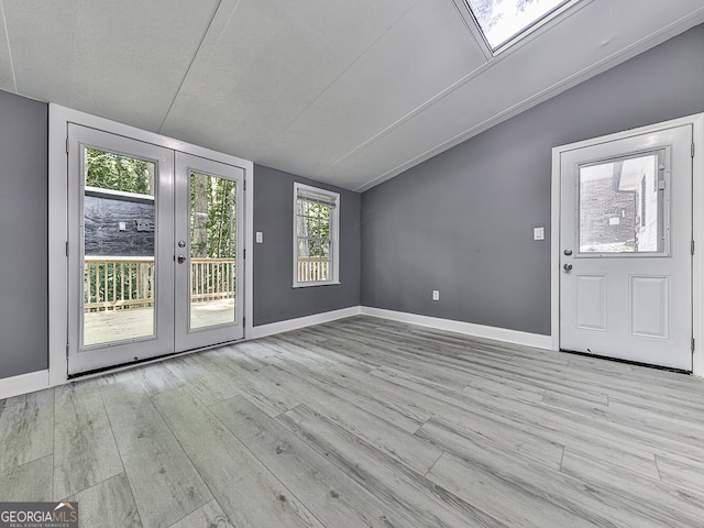 interior space with a textured ceiling, lofted ceiling, french doors, and light hardwood / wood-style flooring