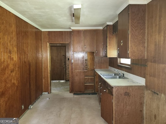 kitchen with wood walls, ornamental molding, sink, and dark brown cabinets