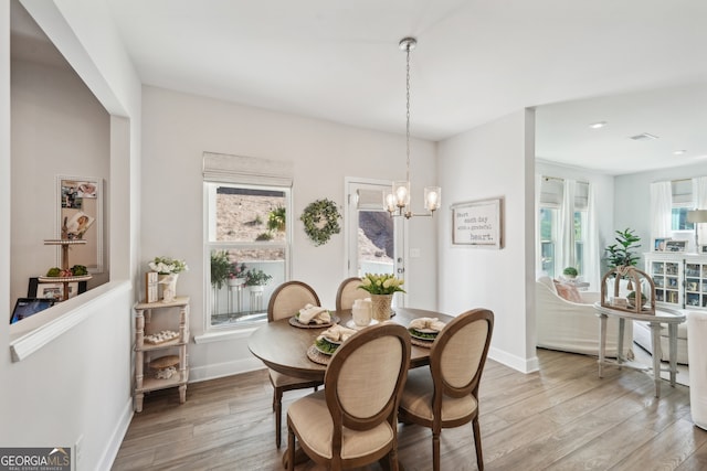 dining room featuring light hardwood / wood-style floors, a notable chandelier, and plenty of natural light