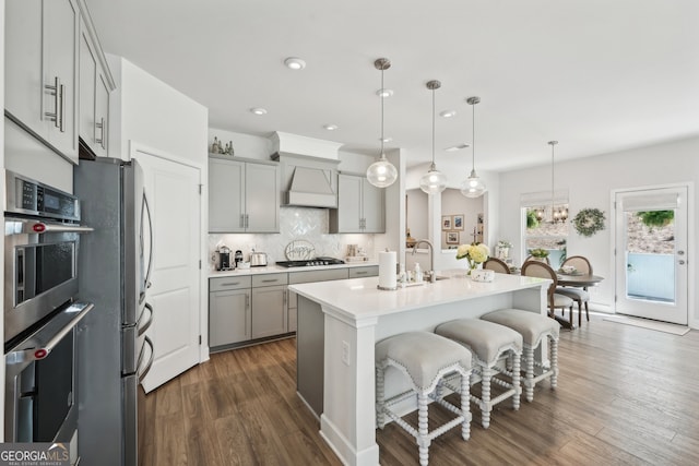 kitchen with gray cabinets, appliances with stainless steel finishes, pendant lighting, and dark hardwood / wood-style flooring