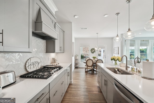 kitchen with dark hardwood / wood-style floors, stainless steel appliances, sink, decorative light fixtures, and gray cabinets