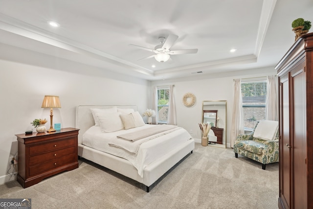 carpeted bedroom with ceiling fan, a raised ceiling, and crown molding