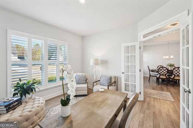 living area featuring an inviting chandelier, french doors, and hardwood / wood-style floors