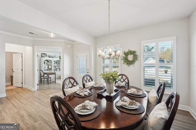 dining space with light hardwood / wood-style floors, an inviting chandelier, and crown molding