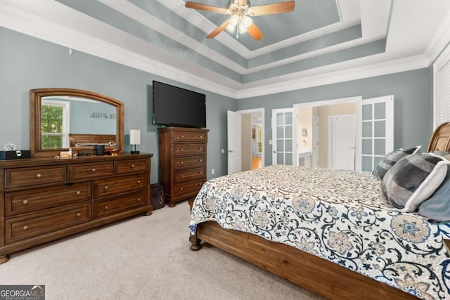 carpeted bedroom with ceiling fan, a raised ceiling, french doors, and ornamental molding