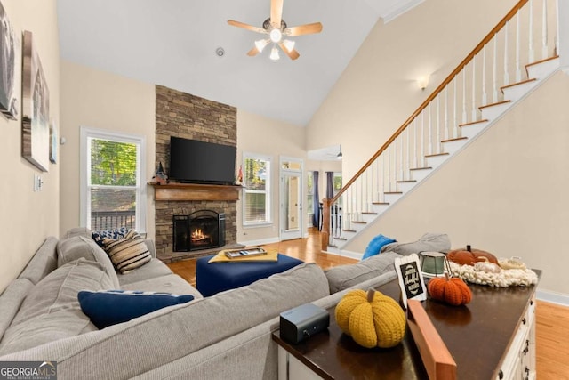 living room featuring a stone fireplace, high vaulted ceiling, and light hardwood / wood-style flooring