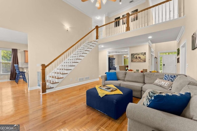 living room featuring a high ceiling, ceiling fan, ornamental molding, and hardwood / wood-style flooring