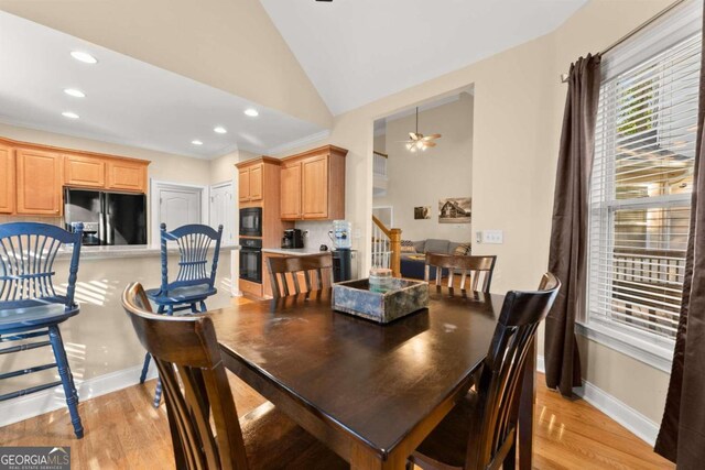 dining space with vaulted ceiling, ceiling fan, and light hardwood / wood-style flooring