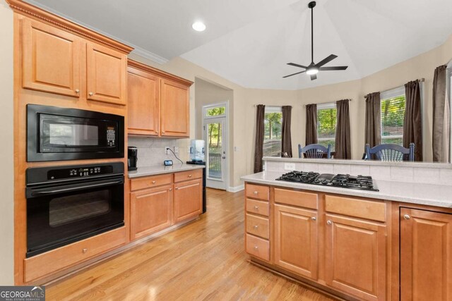 kitchen featuring lofted ceiling, black appliances, tasteful backsplash, ceiling fan, and light hardwood / wood-style flooring