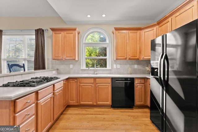 kitchen featuring ornamental molding, light wood-type flooring, black appliances, and backsplash