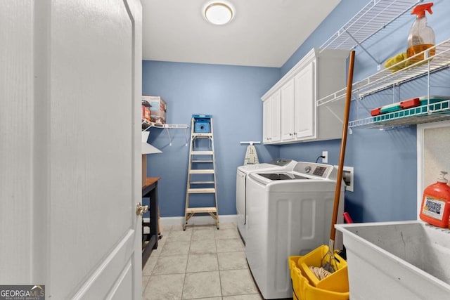 laundry room with cabinets, washing machine and dryer, light tile patterned floors, and sink