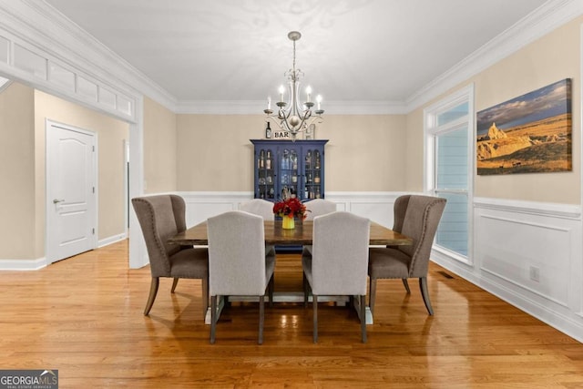 dining area with light hardwood / wood-style flooring, crown molding, and a notable chandelier