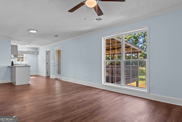 unfurnished living room with ceiling fan, a textured ceiling, crown molding, and dark wood-type flooring