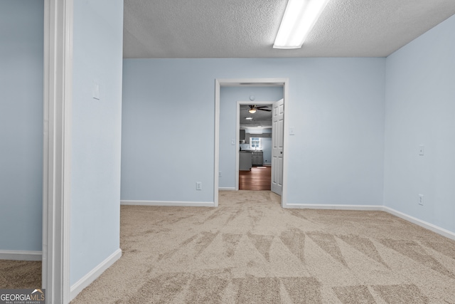 carpeted empty room with ceiling fan and a textured ceiling