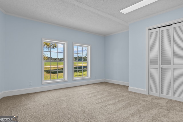 unfurnished bedroom with ornamental molding, a textured ceiling, a closet, and carpet flooring