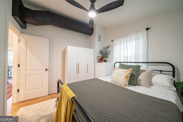 bedroom featuring ceiling fan, light hardwood / wood-style flooring, and multiple windows