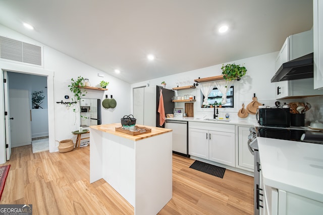 kitchen with ventilation hood, dishwashing machine, vaulted ceiling, sink, and white cabinets