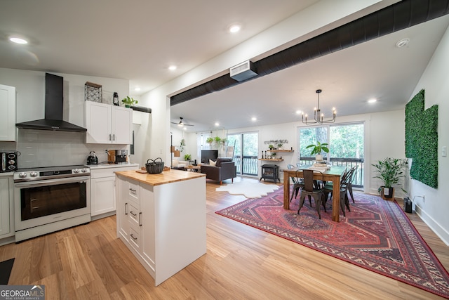 kitchen featuring wall chimney range hood, stainless steel range, light hardwood / wood-style flooring, wood counters, and white cabinetry