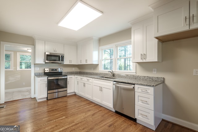 kitchen featuring sink, appliances with stainless steel finishes, light hardwood / wood-style flooring, and white cabinetry