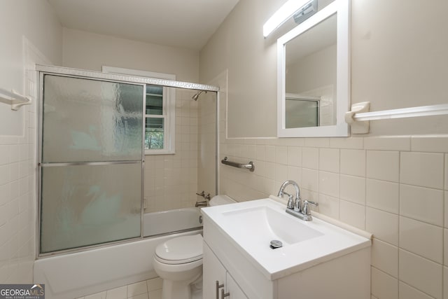 full bathroom featuring vanity, tile walls, toilet, tile patterned flooring, and shower / bath combination with glass door