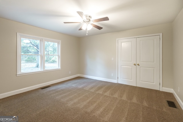 unfurnished bedroom with ceiling fan, a closet, and carpet