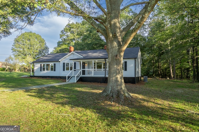 ranch-style home with a front lawn, a porch, and central air condition unit