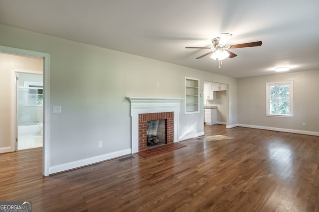 unfurnished living room featuring a brick fireplace, dark hardwood / wood-style flooring, built in features, and ceiling fan