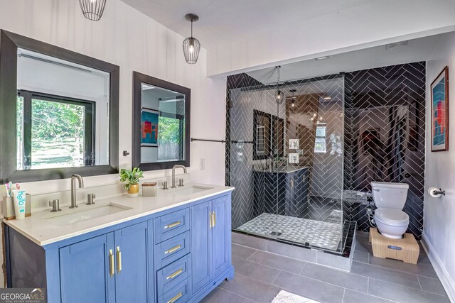 bathroom featuring vanity, toilet, a tile shower, and tile patterned flooring