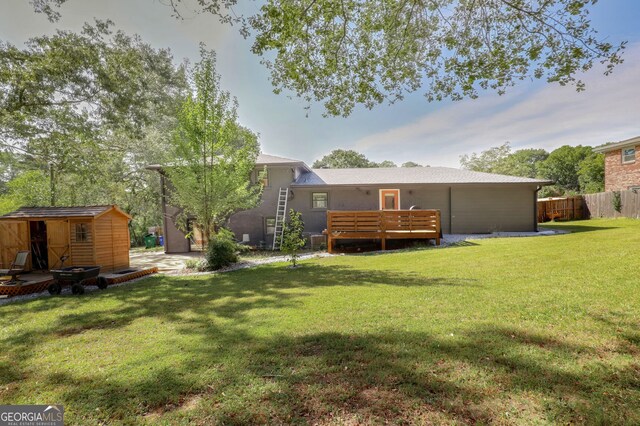 back of house featuring a wooden deck, a storage shed, and a yard