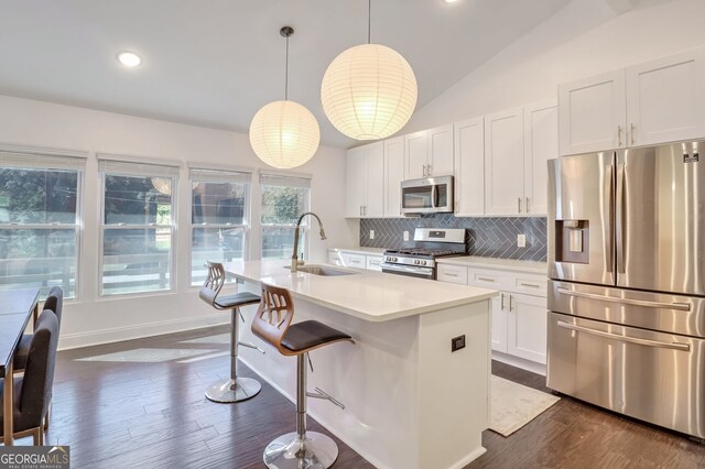 kitchen featuring a center island with sink, sink, vaulted ceiling, pendant lighting, and appliances with stainless steel finishes