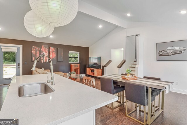 kitchen featuring an island with sink, a kitchen bar, dark wood-type flooring, lofted ceiling with beams, and sink