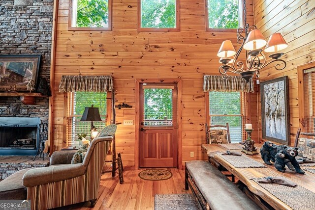 dining area featuring wood walls, a fireplace, an inviting chandelier, and light wood-type flooring