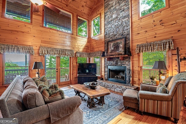 living room with wooden walls, hardwood / wood-style floors, and high vaulted ceiling